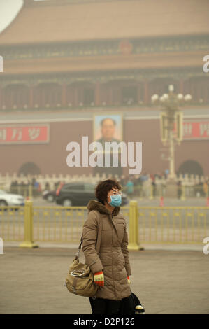 Eine Frau trägt eine Maske auf dem Tiananmen-Platz in dicker Nebel in Peking, China. 30. Januar 2013 Stockfoto