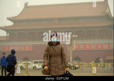 Eine Frau trägt eine Maske auf dem Tiananmen-Platz in dicker Nebel in Peking, China. 30. Januar 2013 Stockfoto