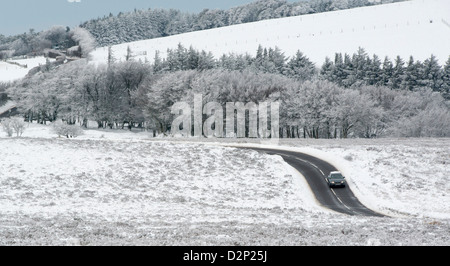 Ein Auto fährt entlang der A39 Somerset zwischen Porlock und Lynton in einer Winterlandschaft Schnee bereift, Exmoor Stockfoto