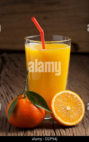 Frisch gepresster Orangensaft mit einem Trinkhalm auf einem alten Holztisch Stockfoto