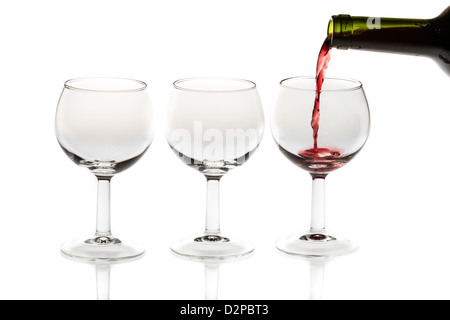 Rotwein Gießen in Glas von Flasche auf weißem Hintergrund Stockfoto