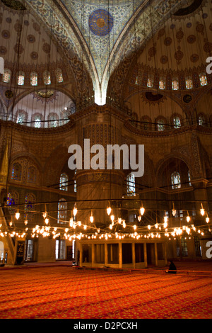 ISTANBUL TÜRKEI - Blaue Moschee (Sultan Ahmet Camii) Innenraum mit muslimischen Mann, der betet auf rotem Bodenbelag, Sultanahmet Stockfoto