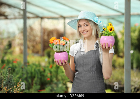 Junge weibliche Gärtner halten Blumentöpfe in einem Garten Stockfoto