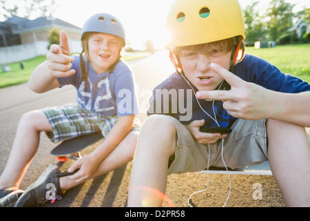 Kaukasischen jungen sitzen auf Skateboards und Gesten Stockfoto