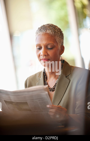 Afrikanische amerikanische Geschäftsfrau Zeitunglesen im café Stockfoto