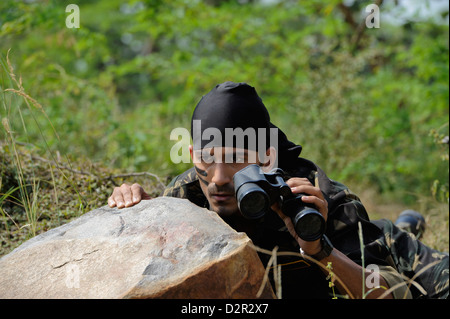 Soldat, versteckt sich hinter einem Felsen mit dem Fernglas Stockfoto