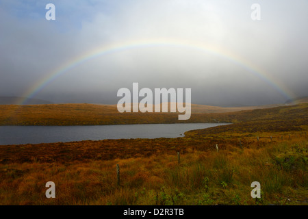 Gewitterhimmel und Regenbogen über ein Loch, Highlands, Schottland, Vereinigtes Königreich, Europa Stockfoto