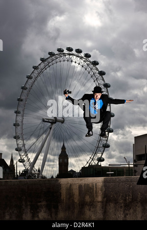 Parkour-Läufer in vollständigen Anzug springen vor London eye Stockfoto