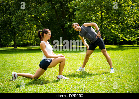 Junger Mann und Frau trainieren und dehnen Sie Muskeln vor sportlichen Aktivitäten - im Freien in der Natur Stockfoto