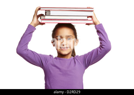 8 jährige Schulmädchen mit Büchern auf dem Kopf auf weißem Hintergrund Stockfoto