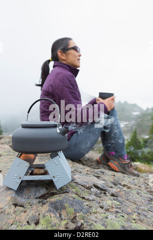 Japanische Frau trinkt Kaffee am Campingplatz Stockfoto