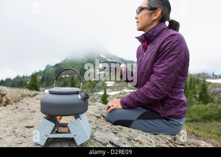 Japanische Frau trinkt Kaffee am Campingplatz Stockfoto