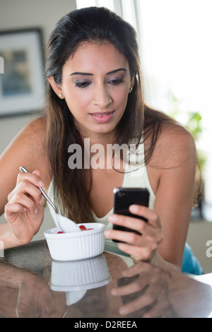 Indische Frau mit Handy und Essen Stockfoto