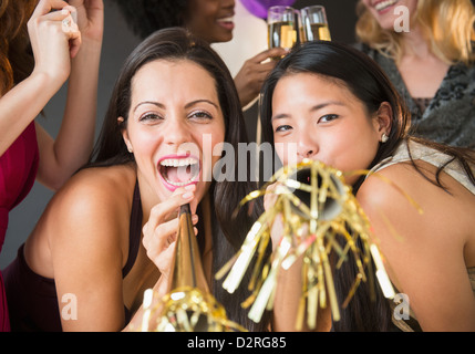 Lächelnde Frauen weht Partei Hörner auf party Stockfoto