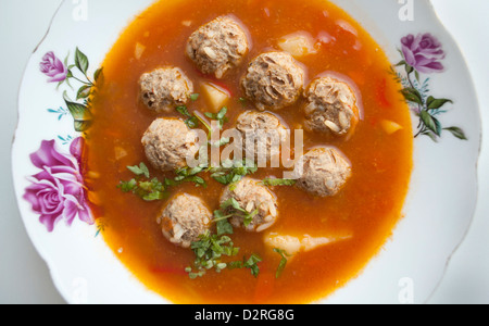 Tomatensuppe mit Fleischklößchen auf einem Teller mit Blumen Stockfoto