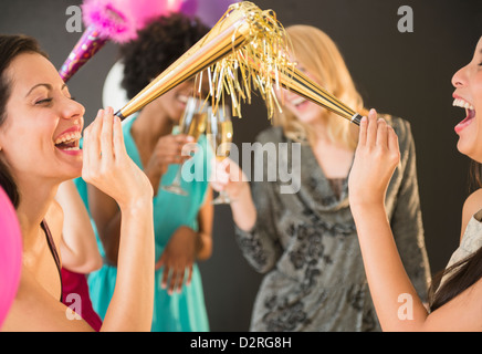 Lächelnde Frauen weht Partei Hörner auf party Stockfoto