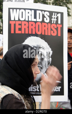 Eine muslimische Frau geht vor einem Anti George Bush Plakat. Stockfoto