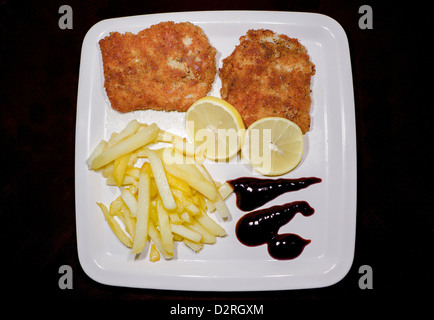 Fisch, Chips, Zitrone und Dressing in einem weißen Teller Stockfoto