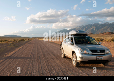 4WD Auto fährt auf einer unbefestigten Straße auf einem Roadtrip durch Owens Valley, Kalifornien in der Nähe von Bischof auf dem Weg zum Red Canyon bei Sonnenuntergang. Stockfoto