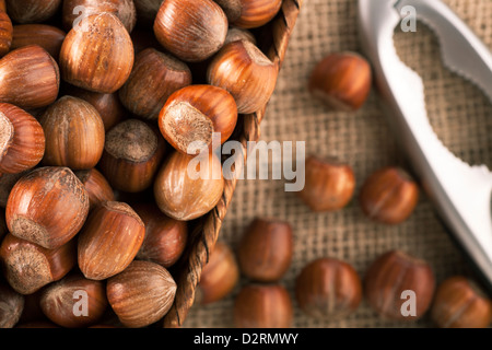 Ganze Haselnüsse in Korb mit Nussknacker auf Tisch, direkt von oben. Stockfoto