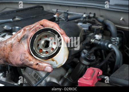 Kfz-Mechaniker zeigt einen alten, schmutzigen Ölfilter nur entfernt von einem Auto während der allgemeinen Wartung Stockfoto