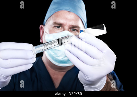 Ein Arzt entzieht Drogen ein Fläschchen in Vorbereitung ein Patienten zu injizieren. Stockfoto