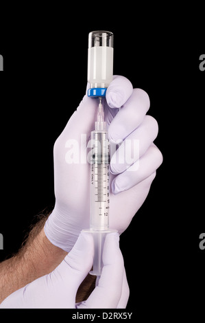 Ein Arzt entzieht Drogen ein Fläschchen in Vorbereitung ein Patienten zu injizieren. Stockfoto