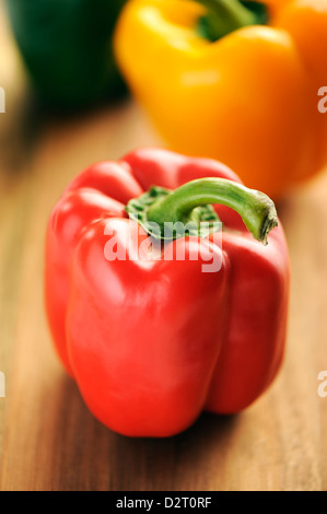 Rote, gelbe und grüne Paprika auf einem hölzernen Hintergrund. Stockfoto