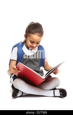 8 Jahre alte Schule Mädchen sitzen Lesebuch mit Rucksack lächelnd auf weißem Hintergrund Stockfoto