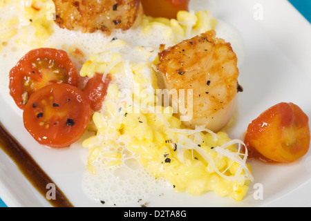 Safran-Risotto mit gegrillten Jakobsmuscheln und Cherry-Tomaten-sauce Stockfoto