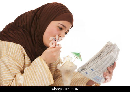 Junge islamische Frau lesen ihre Zeitung und genießen Sie ein Eis Stockfoto