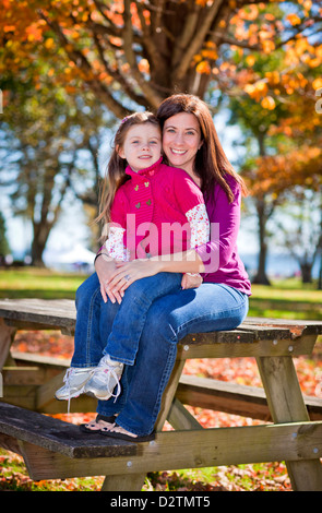 Mutter und Tochter sitzen auf einer Bank im Herbst Stockfoto