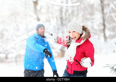 Schneeballschlacht. Glücklich multiethnische Winter Paare, die Spaß im Schnee draußen spielen Stockfoto