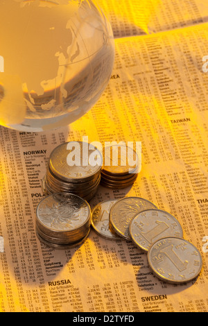 Münzen und Glaskugel auf Finanzzeitung Stockfoto