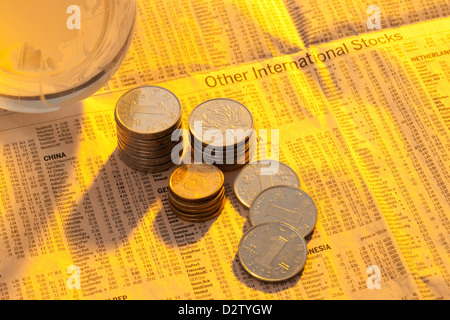 Münzen und Glaskugel auf Seite der Börsenkurse Stockfoto