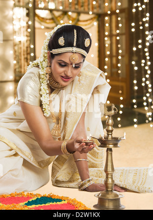 Indische Frau in traditioneller Kleidung, die Beleuchtung einer Öllampe Stockfoto