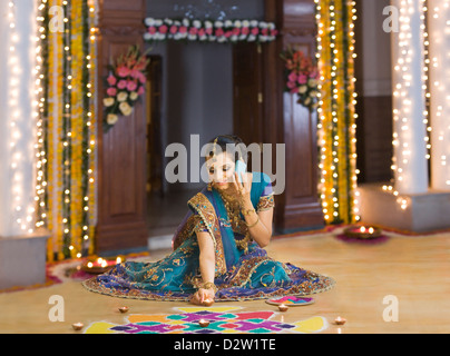 Frau telefonieren mit einem Handy und Vermittlung von Öllampen auf rangoli Stockfoto