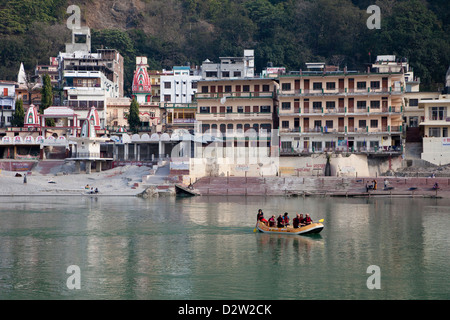 Indien, Rishikesh. Rafting auf dem Ganges (Ganga). Tempel und Pensionen im Hintergrund. Stockfoto