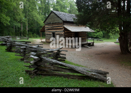 Alte rustikale Blockhütte im Wald mit einem Split Zaun daneben Stockfoto