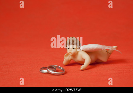 Zwei silberne Ringe mit Engel in rotem Hintergrund Stockfoto