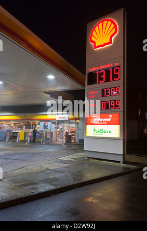 Der Eingang in eine Shell-Tankstelle in der Nacht mit einem Schild mit aktuellen Preisen für Kraftstoff. Stockfoto