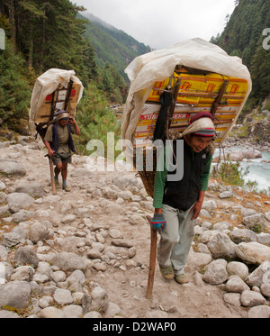 Sherpa-Träger tragen Lieferungen entlang der Everest trek nach Namche Bazar im Himalaya, Nepal. Stockfoto