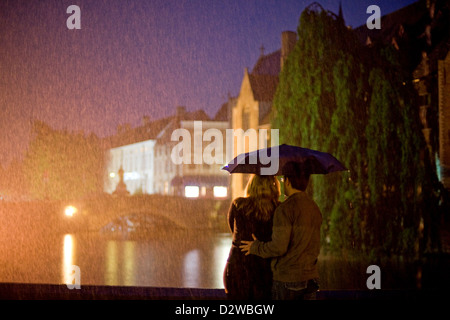 Brügge, Belgien, ein junges Paar unter einem Regenschirm, Blick auf einen Kanal Stockfoto