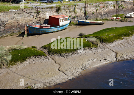 Boote auf Schlammbänke bei Ebbe gegen eine Stützmauer Stockfoto