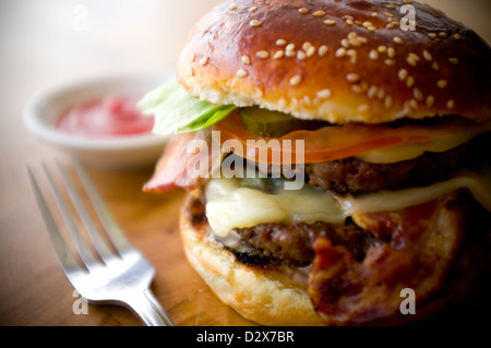 Doppel-Käse - zwei Burger, geschichtet mit Käse, Speck, Tomaten, Salat, Gurke, Zwiebel und Burger-Sauce Stockfoto