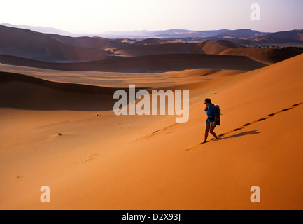 Rucksackreisen Frau hinterlassen Spuren in den Sand Dünen der Namib-Wüste, Namibia, Afrika Stockfoto