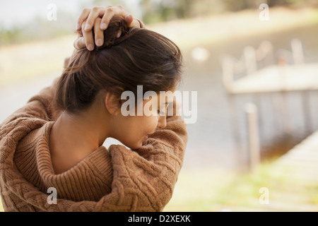 Frau mit Händen in Haar am See Stockfoto