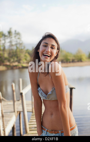 Porträt von begeisterten Frau im Bikini am See Stockfoto