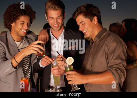 Lächelnde Männer Toasten Cocktails in Nachtclub Stockfoto