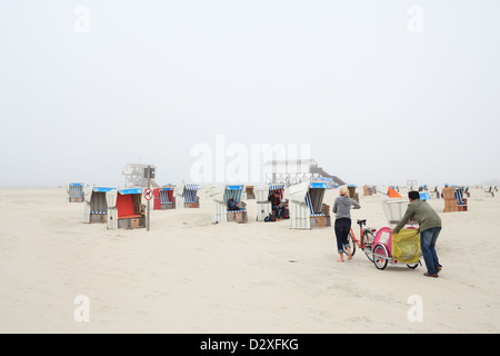 Sankt Peter-Ording, Deutschland, Strandkoerbe und Menschen im Nebel am Strand Stockfoto
